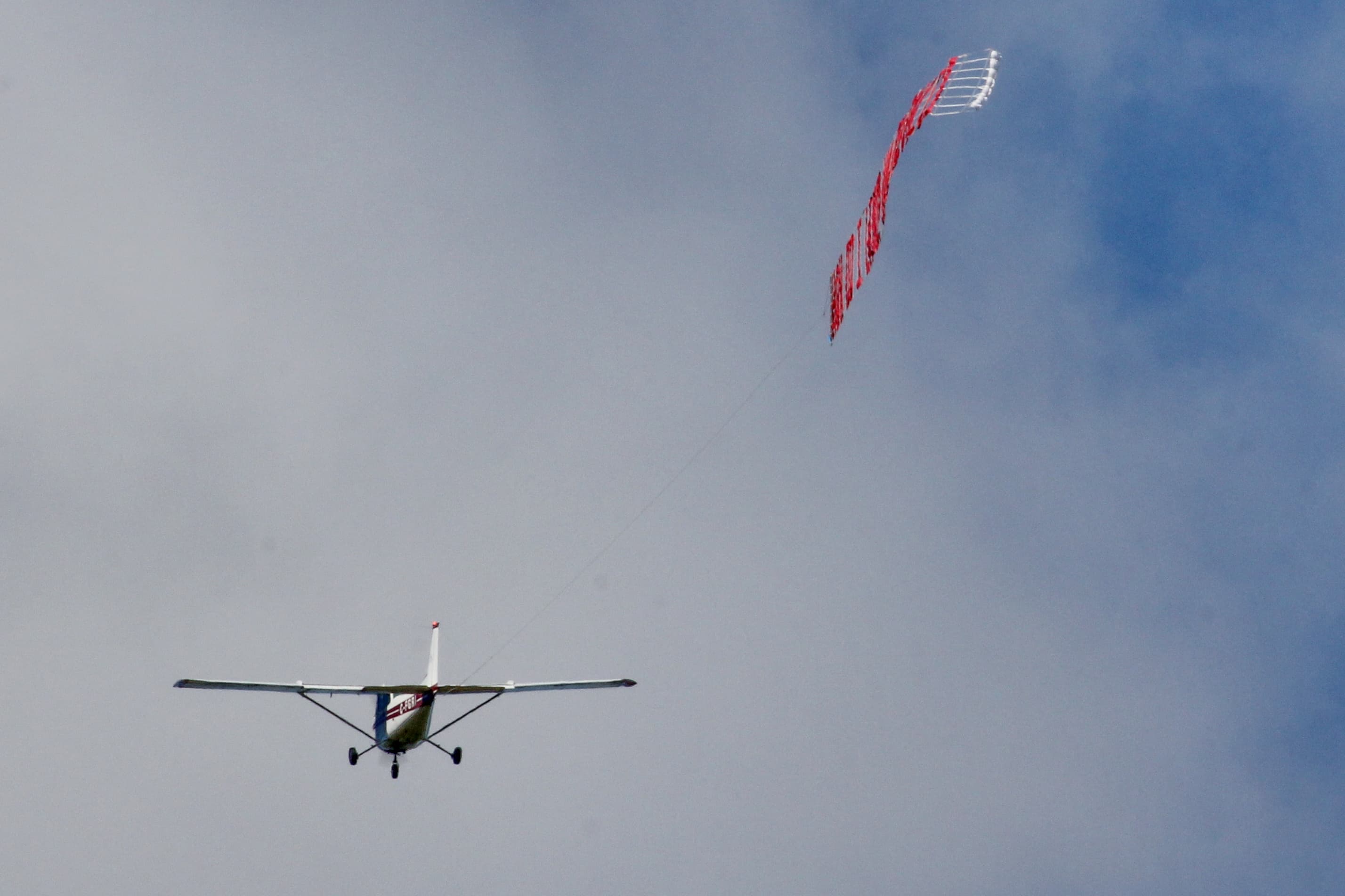Aircraft towing a letter banner through the Southern Ontario sky