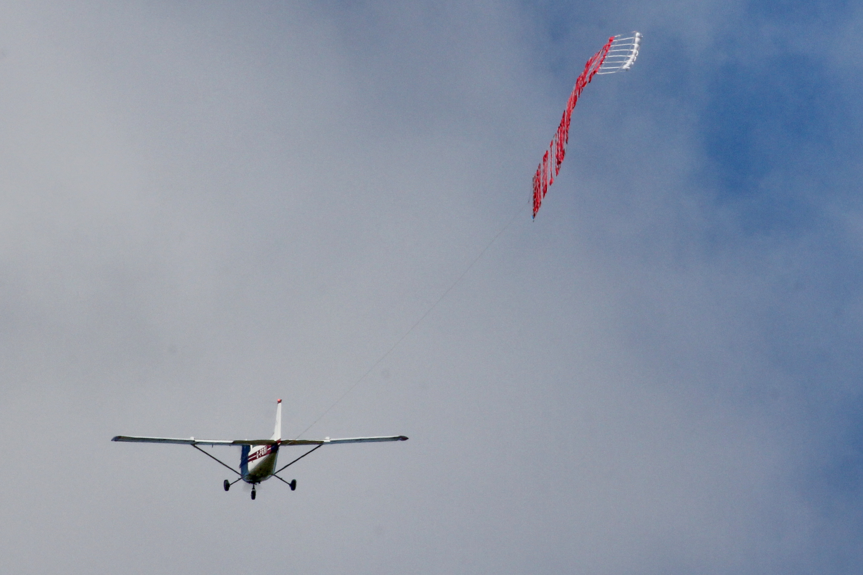 Aircraft towing a letter banner through the Southern Ontario sky